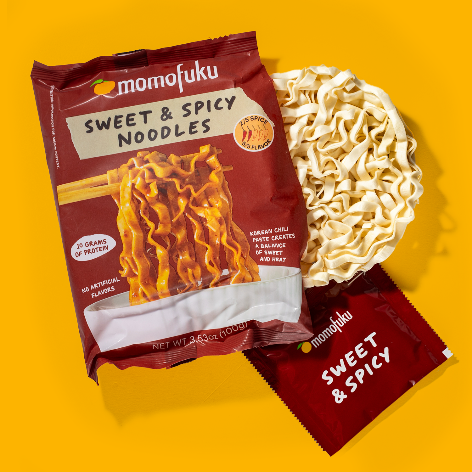 Momofuku Sweet & Spicy Noodles packaging on a yellow background